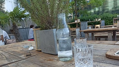 An Holztischen bei Rosmarin und unter Palmen
